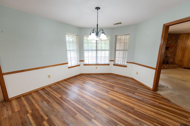 unfurnished dining area with dark hardwood / wood-style flooring and a notable chandelier