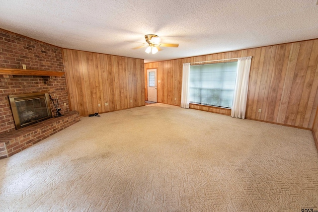 unfurnished living room featuring a textured ceiling, a fireplace, light colored carpet, and wooden walls