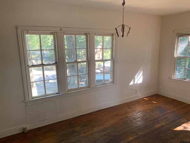 unfurnished dining area featuring dark hardwood / wood-style flooring and a notable chandelier