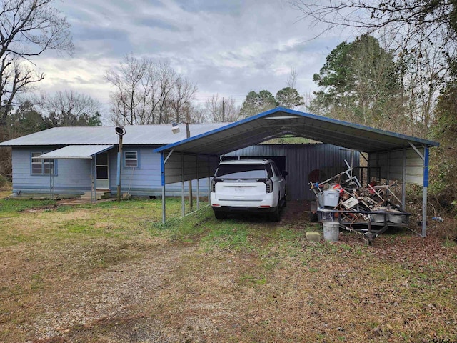 exterior space featuring metal roof, driveway, a front lawn, and a detached carport