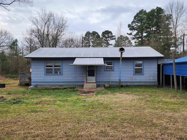 view of front of property featuring entry steps, metal roof, and a front lawn