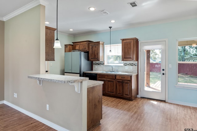 kitchen with stainless steel fridge, kitchen peninsula, a healthy amount of sunlight, and a breakfast bar