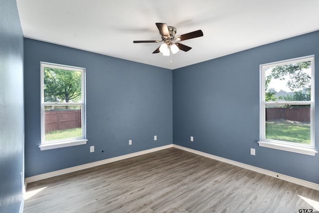 empty room with ceiling fan, hardwood / wood-style flooring, and a healthy amount of sunlight