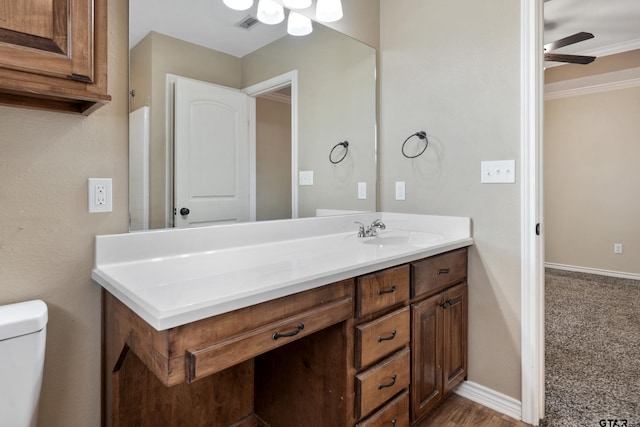 bathroom with ceiling fan, vanity, toilet, and ornamental molding