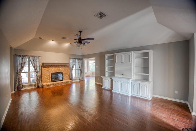 unfurnished living room with hardwood / wood-style floors, ceiling fan, a stone fireplace, and lofted ceiling