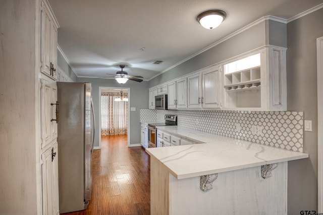 kitchen with light stone countertops, stainless steel appliances, kitchen peninsula, white cabinets, and ornamental molding