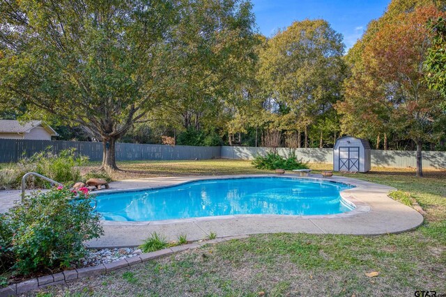 view of swimming pool featuring a diving board, a yard, and a storage shed