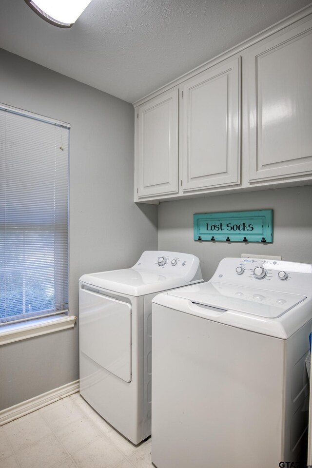 clothes washing area featuring washer and clothes dryer and cabinets