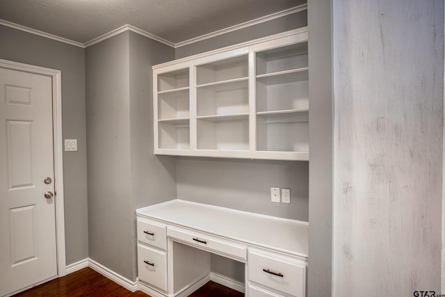 unfurnished office with a textured ceiling, built in desk, dark hardwood / wood-style floors, and crown molding