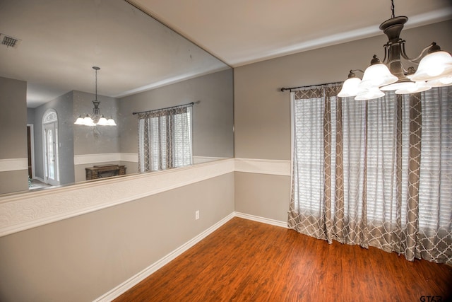 unfurnished dining area with a chandelier and wood-type flooring