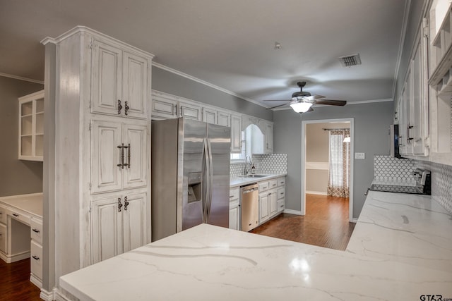 kitchen featuring tasteful backsplash, light stone countertops, white cabinets, and appliances with stainless steel finishes