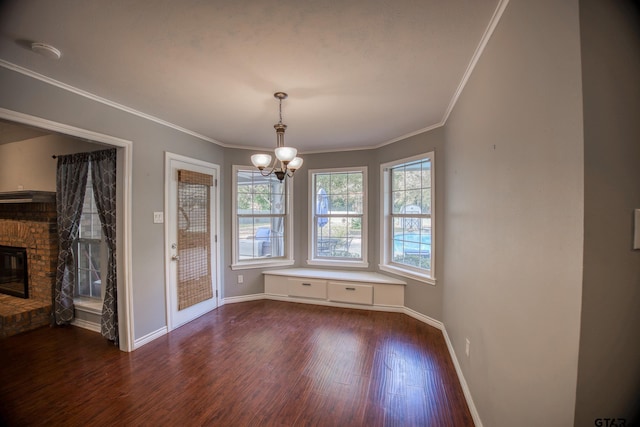 unfurnished dining area featuring dark hardwood / wood-style flooring, a fireplace, a healthy amount of sunlight, and an inviting chandelier