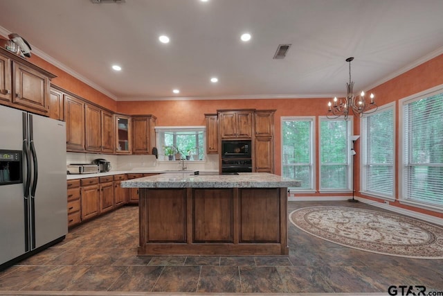 3606 Brookview Ct, Tyler, TX 75707 - kitchen featuring black appliances, a kitchen island, a chandelier, brown cabinets, and glass insert cabinets
