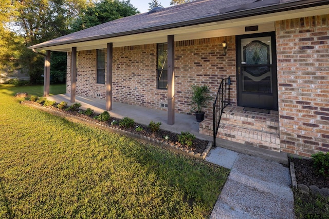 doorway to property featuring covered porch and a lawn