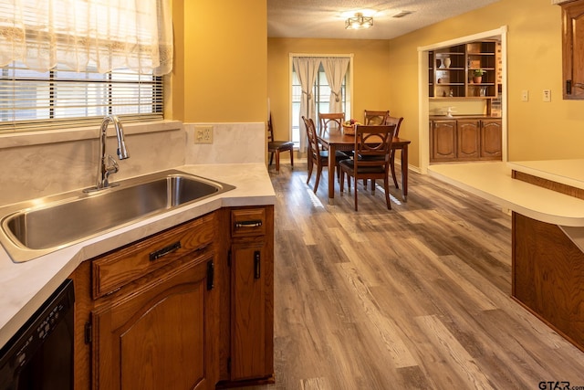 kitchen featuring hardwood / wood-style flooring, black dishwasher, sink, and a textured ceiling