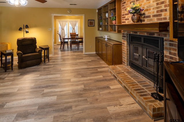 interior space with ceiling fan, a fireplace, and light wood-type flooring