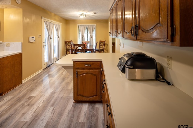 kitchen featuring wood-type flooring, kitchen peninsula, and a textured ceiling