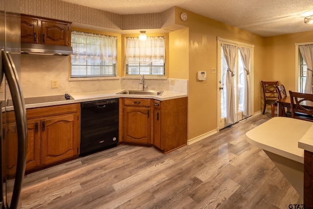 kitchen with light hardwood / wood-style floors, sink, a textured ceiling, and black appliances