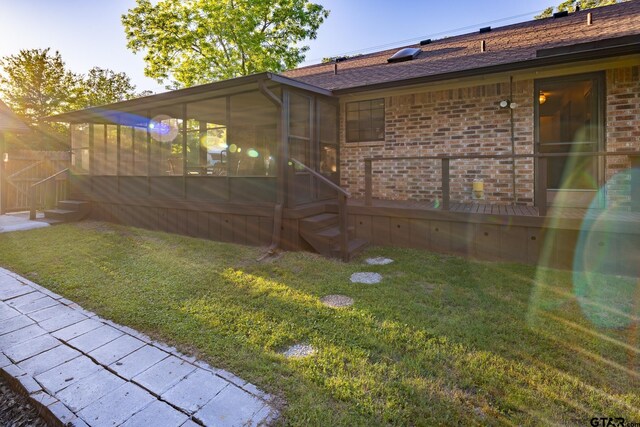 rear view of house with a yard and a sunroom