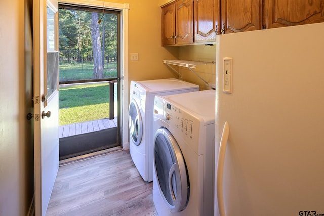 washroom with cabinets, washer and dryer, and light hardwood / wood-style flooring