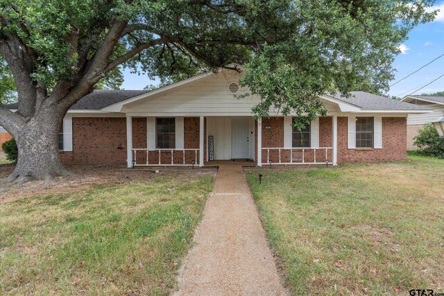 ranch-style house featuring a front lawn and covered porch