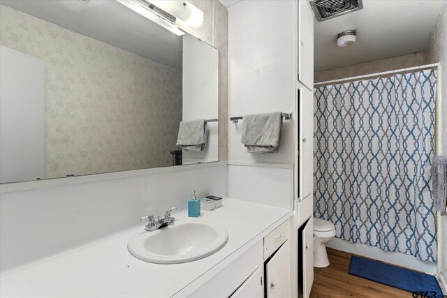 bathroom with toilet, a shower with curtain, vanity, and hardwood / wood-style flooring