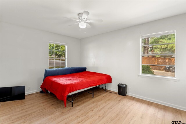 bedroom with light wood-type flooring, multiple windows, and ceiling fan