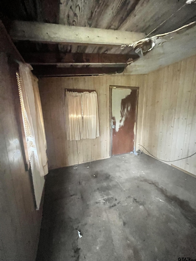 spare room featuring concrete flooring and wood walls