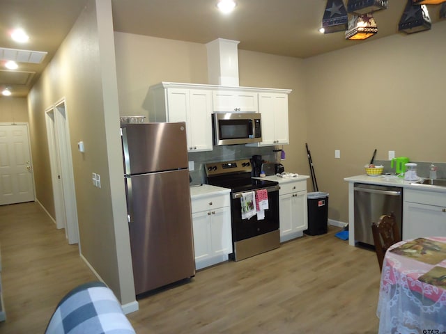 1323 Cummins St, Palestine, TX 75801 - kitchen with appliances with stainless steel finishes, white cabinetry, light wood-type flooring, backsplash, and recessed lighting