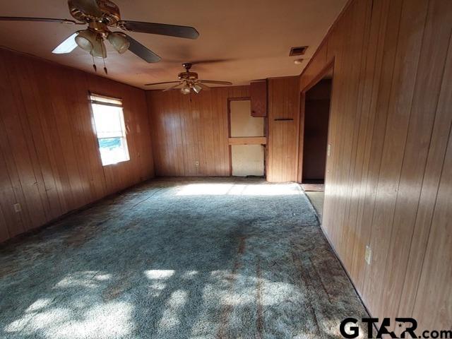 2401 E Fm 852, Winnsboro, TX 75494 - unfurnished room featuring wooden walls, a ceiling fan, visible vents, and light carpet