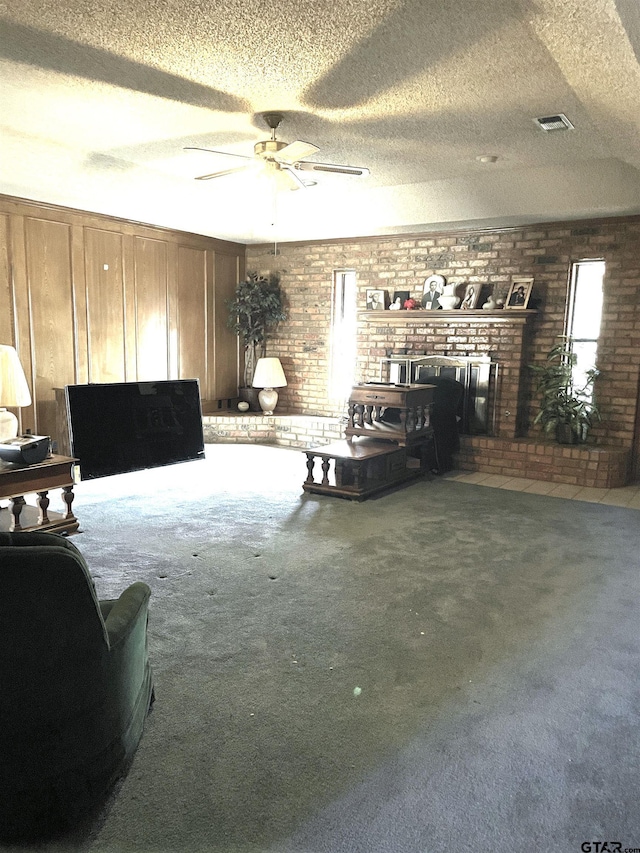 living room with brick wall, carpet flooring, a textured ceiling, and ceiling fan