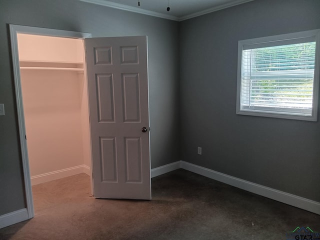 unfurnished bedroom with baseboards, carpet flooring, a closet, and crown molding