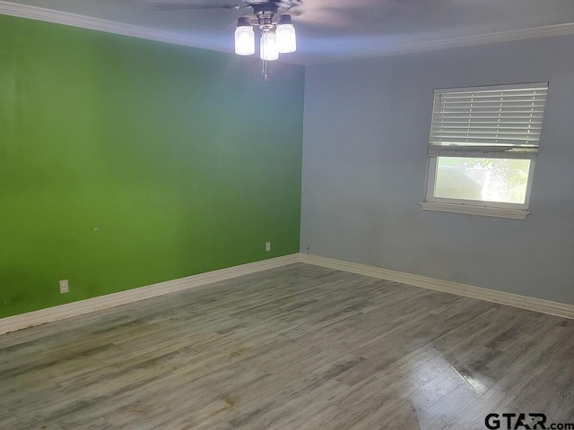 spare room with crown molding, ceiling fan, baseboards, and wood finished floors