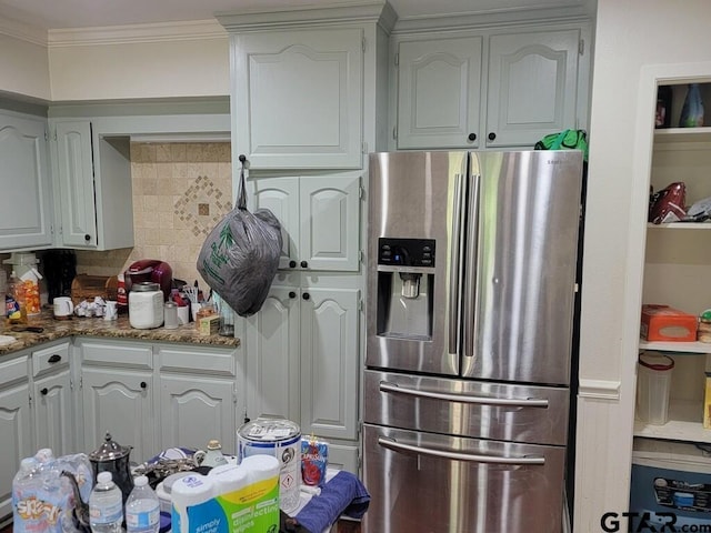 kitchen with crown molding, decorative backsplash, light stone countertops, stainless steel refrigerator with ice dispenser, and white cabinets