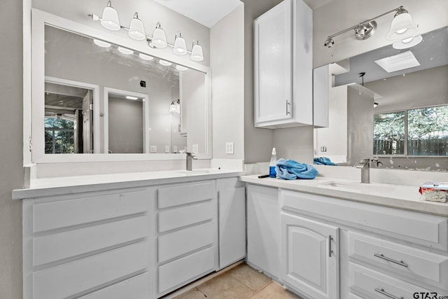 bathroom with tile patterned flooring, vanity, and a skylight