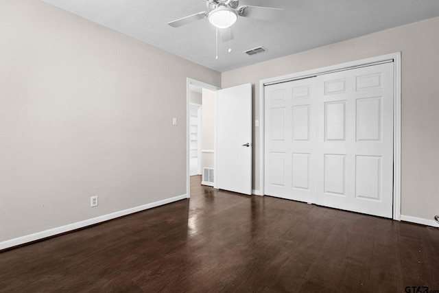 unfurnished bedroom with ceiling fan, dark hardwood / wood-style flooring, and a closet