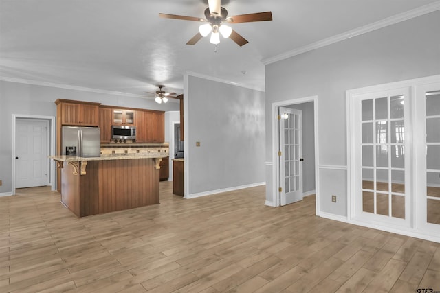 kitchen with ceiling fan, light hardwood / wood-style floors, appliances with stainless steel finishes, a kitchen breakfast bar, and ornamental molding