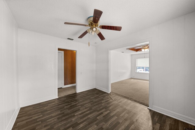 spare room with a textured ceiling, ceiling fan, and dark hardwood / wood-style floors