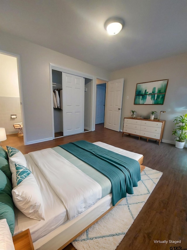 bedroom featuring dark hardwood / wood-style floors, ensuite bath, and a closet