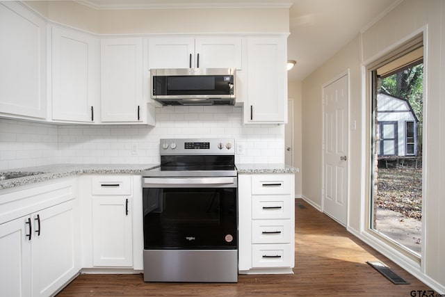 kitchen with light stone countertops, dark hardwood / wood-style flooring, ornamental molding, stainless steel appliances, and white cabinets