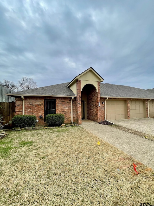 single story home featuring a garage, driveway, roof with shingles, a front lawn, and brick siding