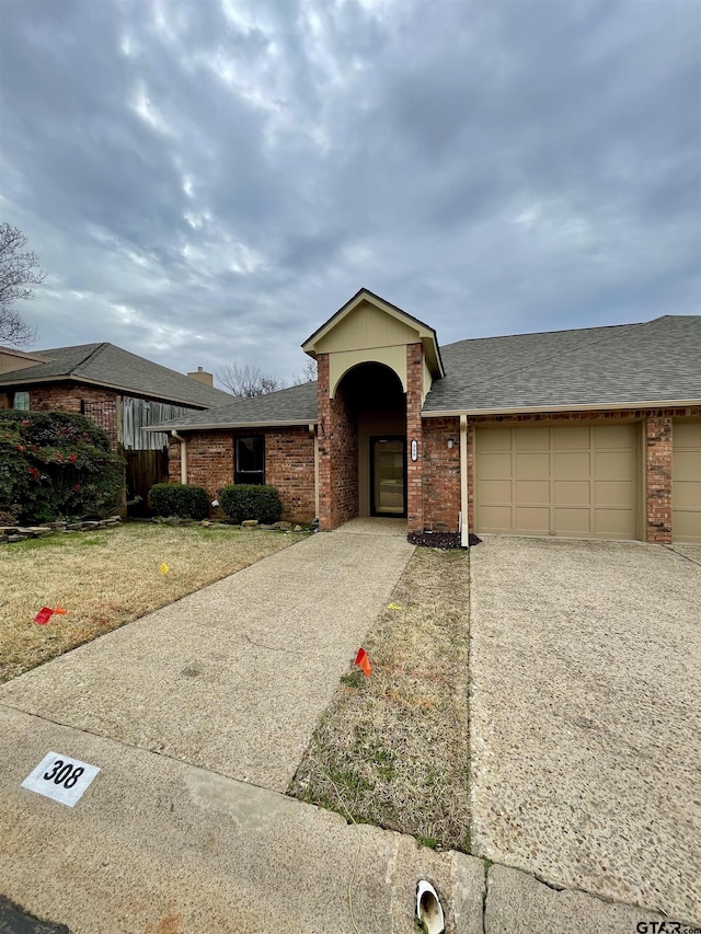 view of front of home featuring a shingled roof, concrete driveway, brick siding, and an attached garage