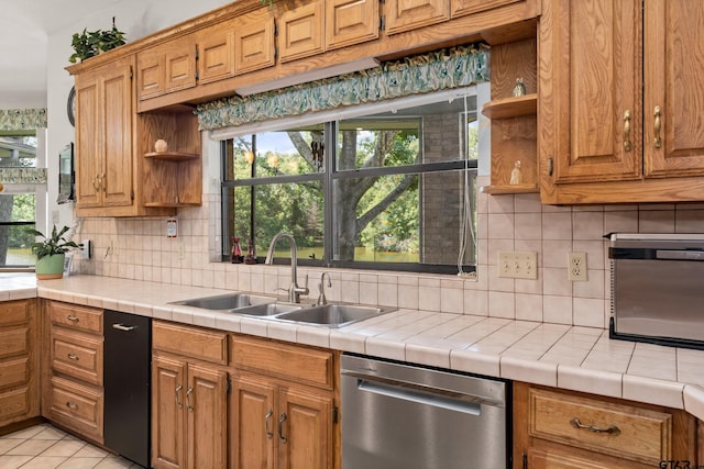 kitchen with tile countertops, decorative backsplash, dishwasher, and sink