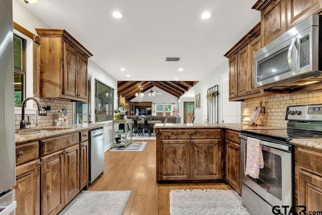 425 Lakeview Dr, Hideaway, TX 75771 - kitchen featuring stainless steel appliances, a sink, light wood finished floors, vaulted ceiling, and a peninsula