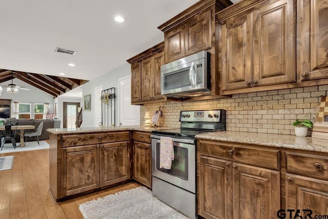 425 Lakeview Dr, Hideaway, TX 75771 - kitchen with stainless steel appliances, a peninsula, light wood-style floors, light stone counters, and vaulted ceiling