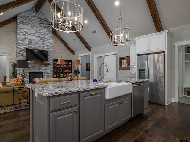 kitchen with a barn door, stainless steel appliances, a sink, and gray cabinetry