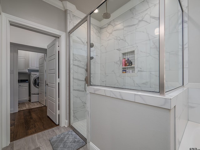 bathroom with washer / clothes dryer, a marble finish shower, and wood finished floors