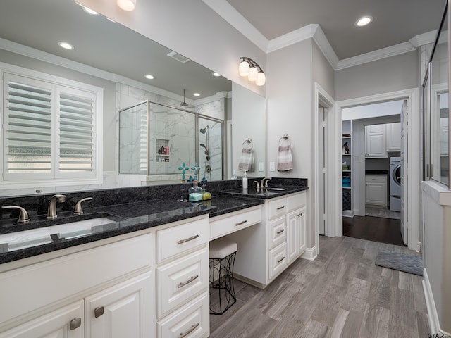 full bathroom with wood finished floors, a sink, ornamental molding, a shower stall, and washer / dryer