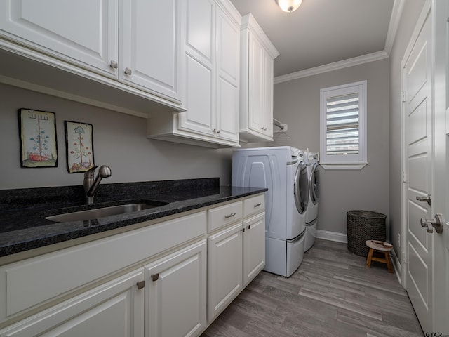 clothes washing area featuring washing machine and dryer, a sink, ornamental molding, cabinet space, and light wood finished floors