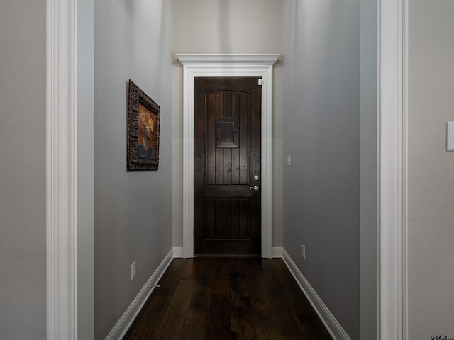 doorway featuring baseboards and dark wood-style flooring